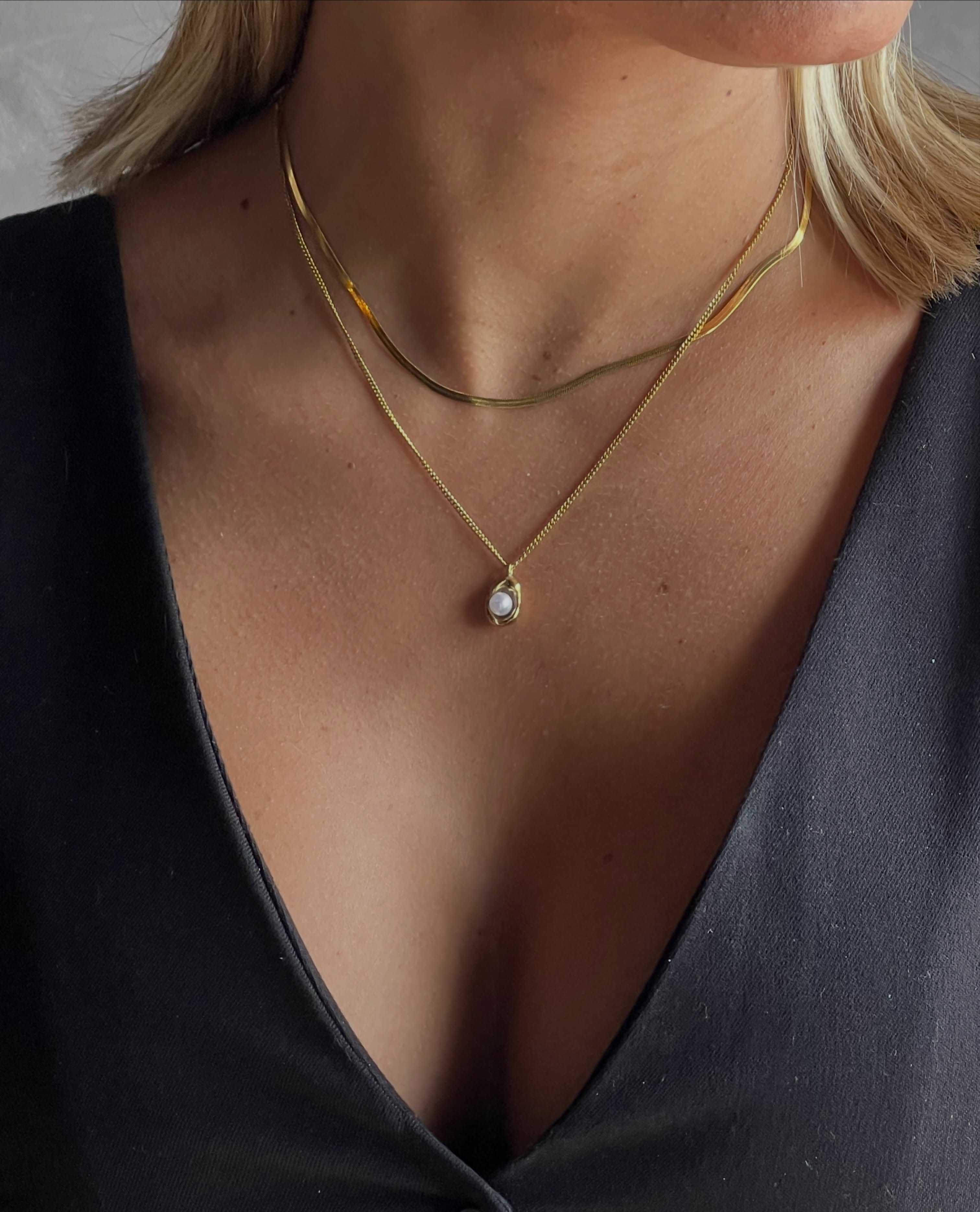 Collares dorados en capas sobre prenda oscura